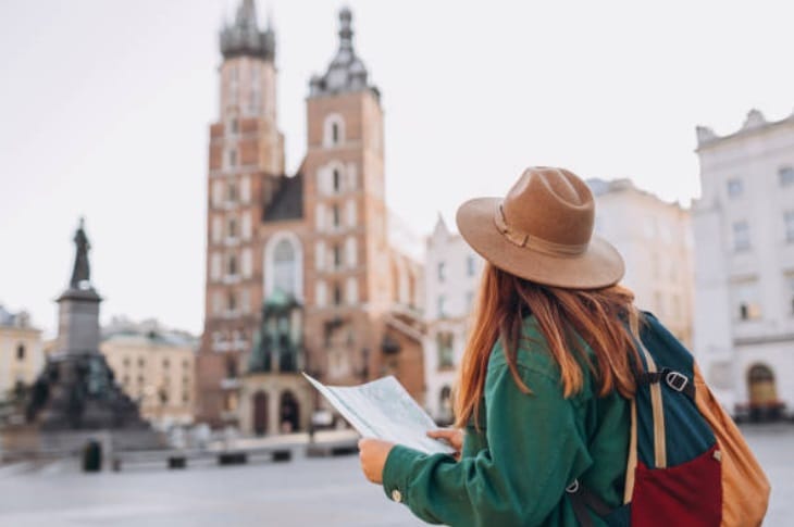 Kobieta z mapą spaceruje jesienią po centrum Krakowa przed Kościołem Mariackim